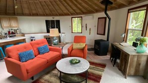 A cozy living room with a wooden ceiling, a sofa, a chair, a coffee table, and a kitchen area in the background. - Retreat to wine country (Amity)