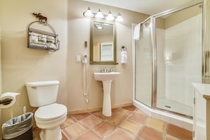A bathroom with a toilet, sink, and glass shower enclosure.