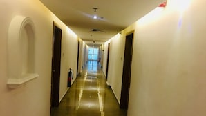 A long, narrow hallway with a polished floor, white walls, and doors on both sides. - Peninsula Hotel & Towers (Lekki)