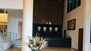 A lobby with a reception desk, a large vase of flowers, a staircase, and clocks on the wall. - Peninsula Hotel & Towers (Lekki)