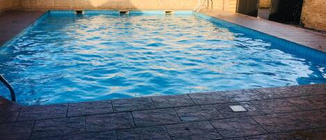 Una piscina al aire libre, sombrillas, sillones reclinables de piscina