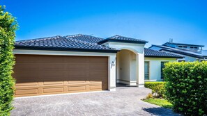 A residential house with a garage, a driveway, and a well-maintained lawn.