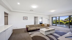 A modern living room with a sofa, coffee table, and a view of the outdoors.