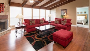 A spacious living room with a fireplace, red sofas, a coffee table, and a ceiling fan.