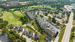 Ett flygbildsfoto av ett bostadsområde med flera hyreshus, en golfbana och en stor parkeringsplats.