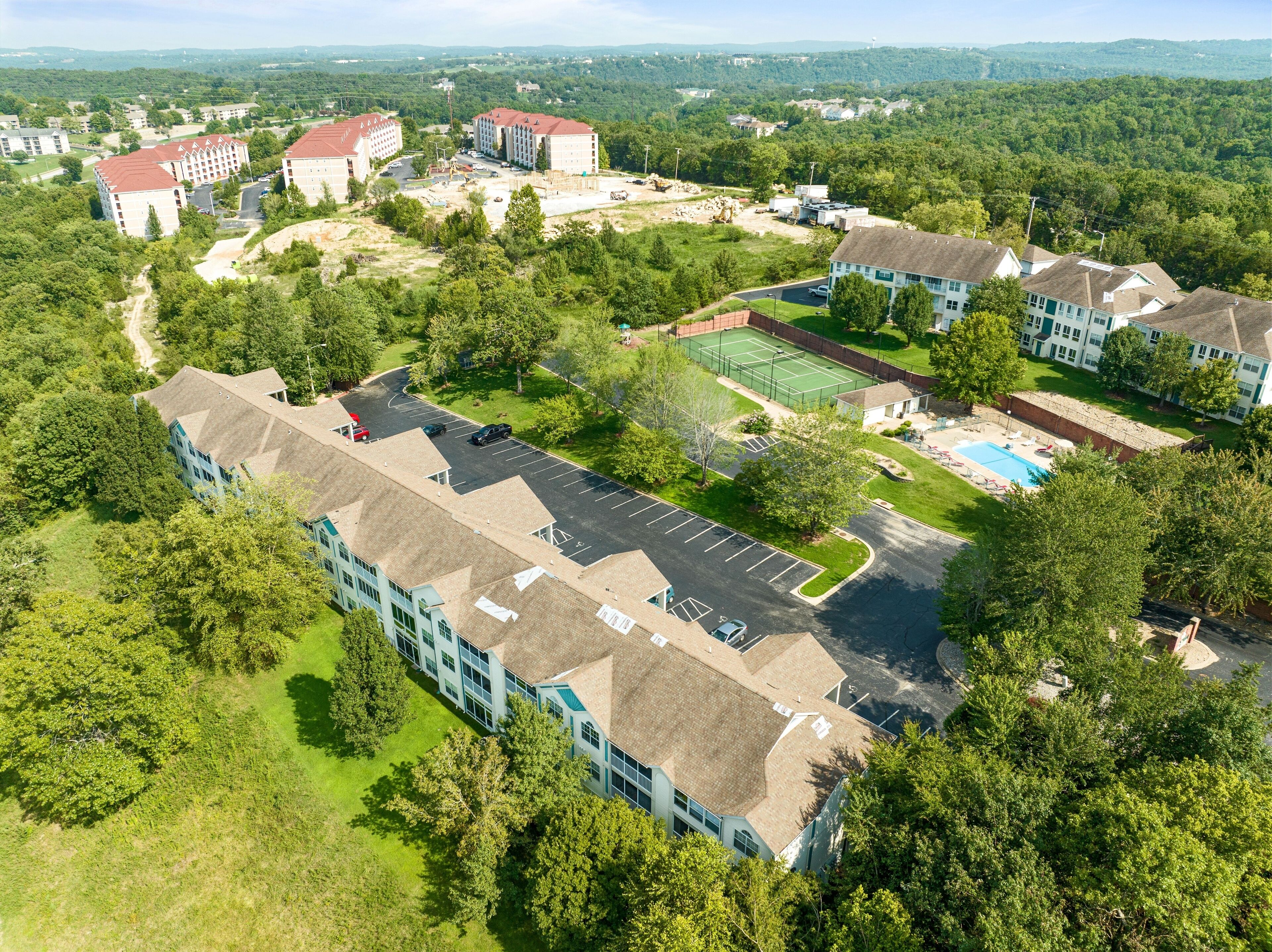 Vue aérienne d’un quartier résidentiel comprenant plusieurs immeubles d’appartements, un court de tennis et une piscine.
