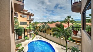 Un edificio residenziale con piscina, balconi e vista su palme e montagne.