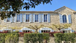 A stone building with multiple windows and shutters, surrounded by potted plants and a clear sky. - 2-room apartment with terrace 800 meters from the beaches (CANNES)