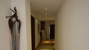 A hotel hallway with a wooden floor, a white wall with a decorative item, and a door at the end. - Aparthotel Paradies (Bad Salzschlirf)