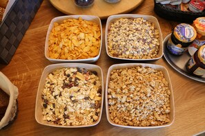 Four rectangular trays of granola on a wooden table. - Aparthotel Paradies (Bad Salzschlirf)