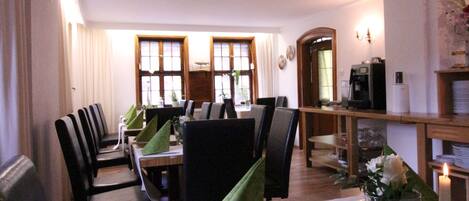 A dining area with tables set for two, chairs, and a coffee machine.