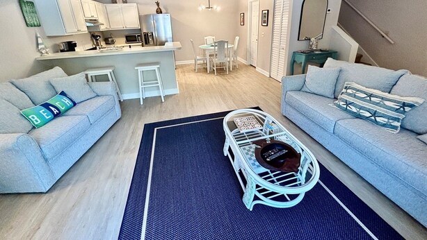 Een modern appartement met twee banken, een eethoek, een keuken en een trap.