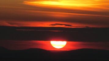 A sunset over a body of water with a silhouette of a mountain range.