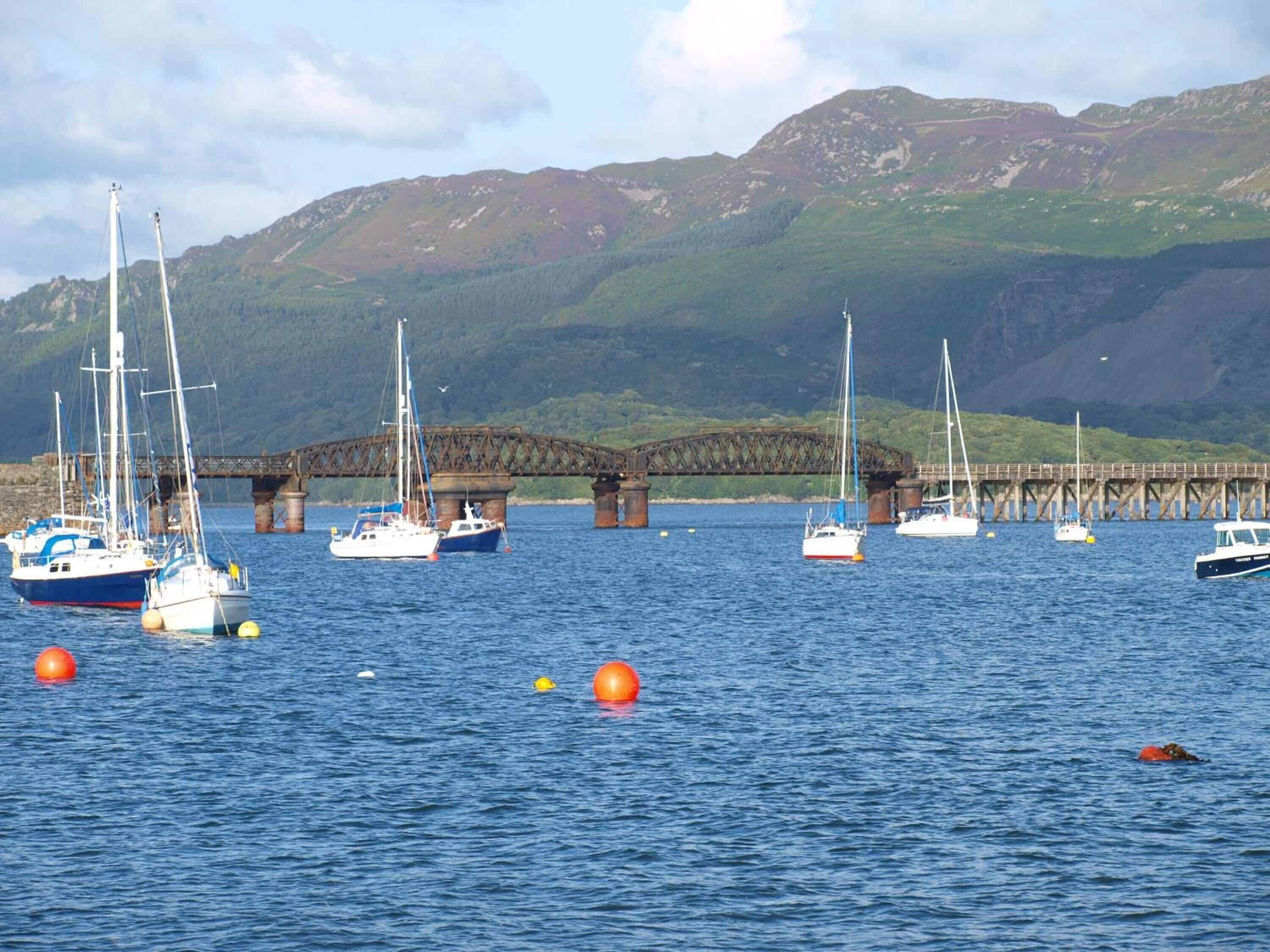 A harbor with boats, a bridge, and mountains in the background.