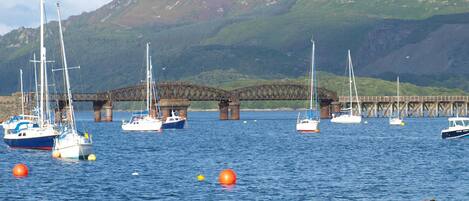 A harbor with boats, a bridge, and mountains in the background.