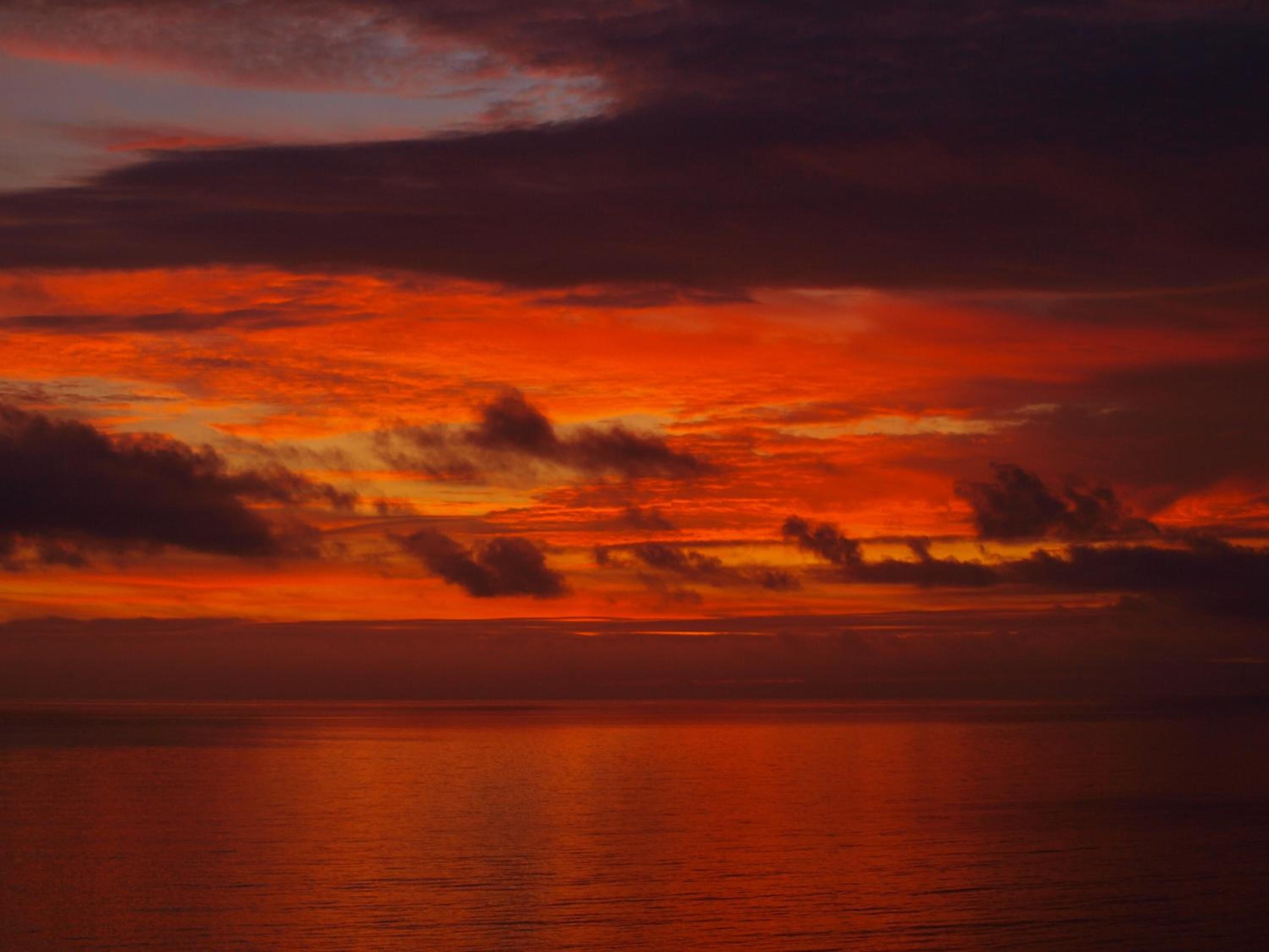 A sunset over a calm body of water with a clear horizon.