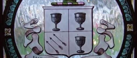 Una ventana de vitral con un escudo de armas que muestra una figura en un escudo, dos leones y la inscripción "VIRTUTE ET INNOCENTIA".