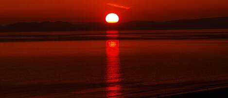 Un atardecer sobre una masa de agua tranquila, con horizonte visible.