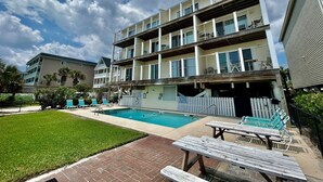 A multi-story building with a swimming pool, outdoor seating, and a well-maintained lawn. - South Shores I 3 2 Bedroom Condo by RedAwning (Surfside Beach)
