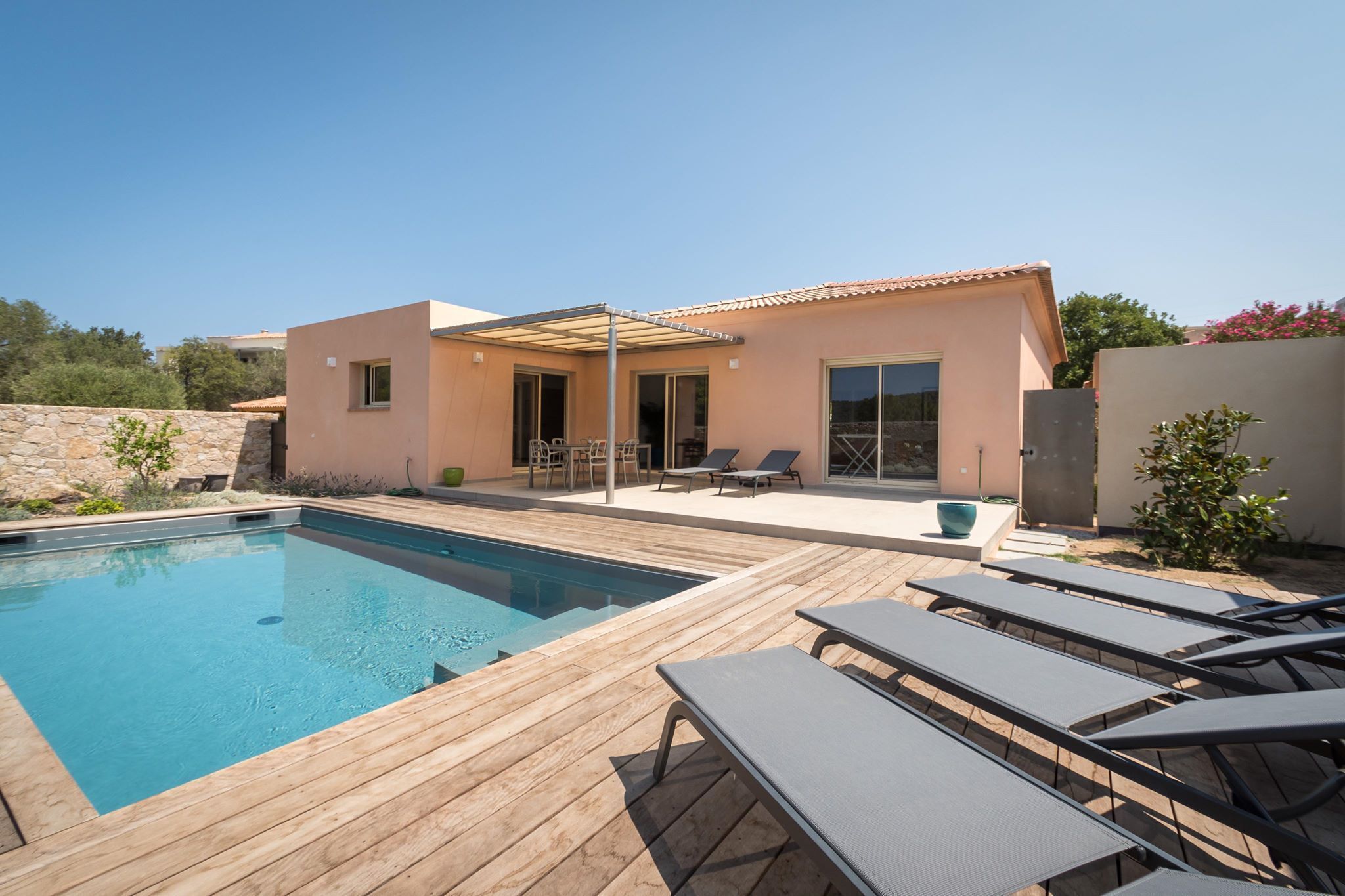 Ein modernes Haus mit Swimmingpool, Sitzgelegenheit im Freien und einer überdachten Terrasse.