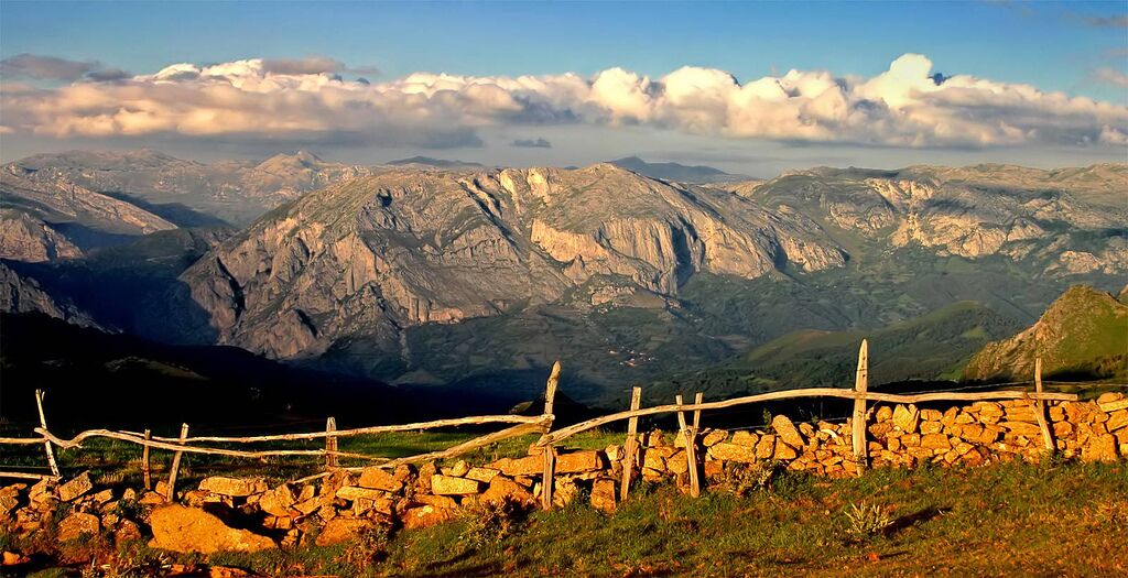 Paisaje montañoso con una cerca de piedra y un muro de piedra en primer plano.