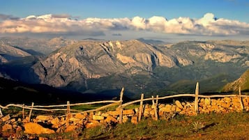 A mountainous landscape with a stone fence and a stone wall in the foreground.