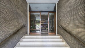 A staircase with a herringbone-patterned floor leading to a glass door entrance.