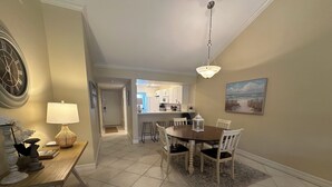 A dining area with a round table, chairs, a lamp, and a clock on the wall. - Enjoy the tranquility of this spacious two bedroom unit. Siesta Dunes 6-203 (Siesta Key)