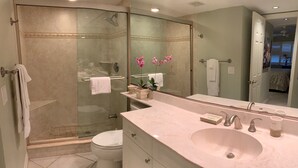 A modern bathroom with a glass-enclosed shower, a white toilet, a vanity with a large sink, and a mirror. - Enjoy the tranquility of this spacious two bedroom unit. Siesta Dunes 6-203 (Siesta Key)