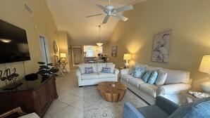 A living room with a ceiling fan, two couches, a coffee table, and a TV. - Enjoy the tranquility of this spacious two bedroom unit. Siesta Dunes 6-203 (Siesta Key)