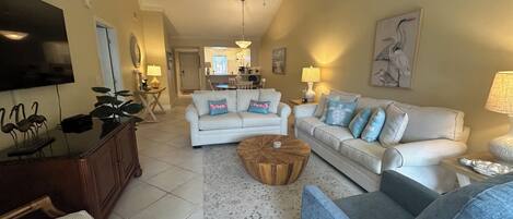 A living room with a ceiling fan, two couches, a coffee table, and a TV.