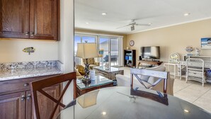 A spacious living area with a dining table, chairs, a TV, and a ceiling fan. - Sandpiper Cove 2136 2 Bedroom Condo by RedAwning (Destin)