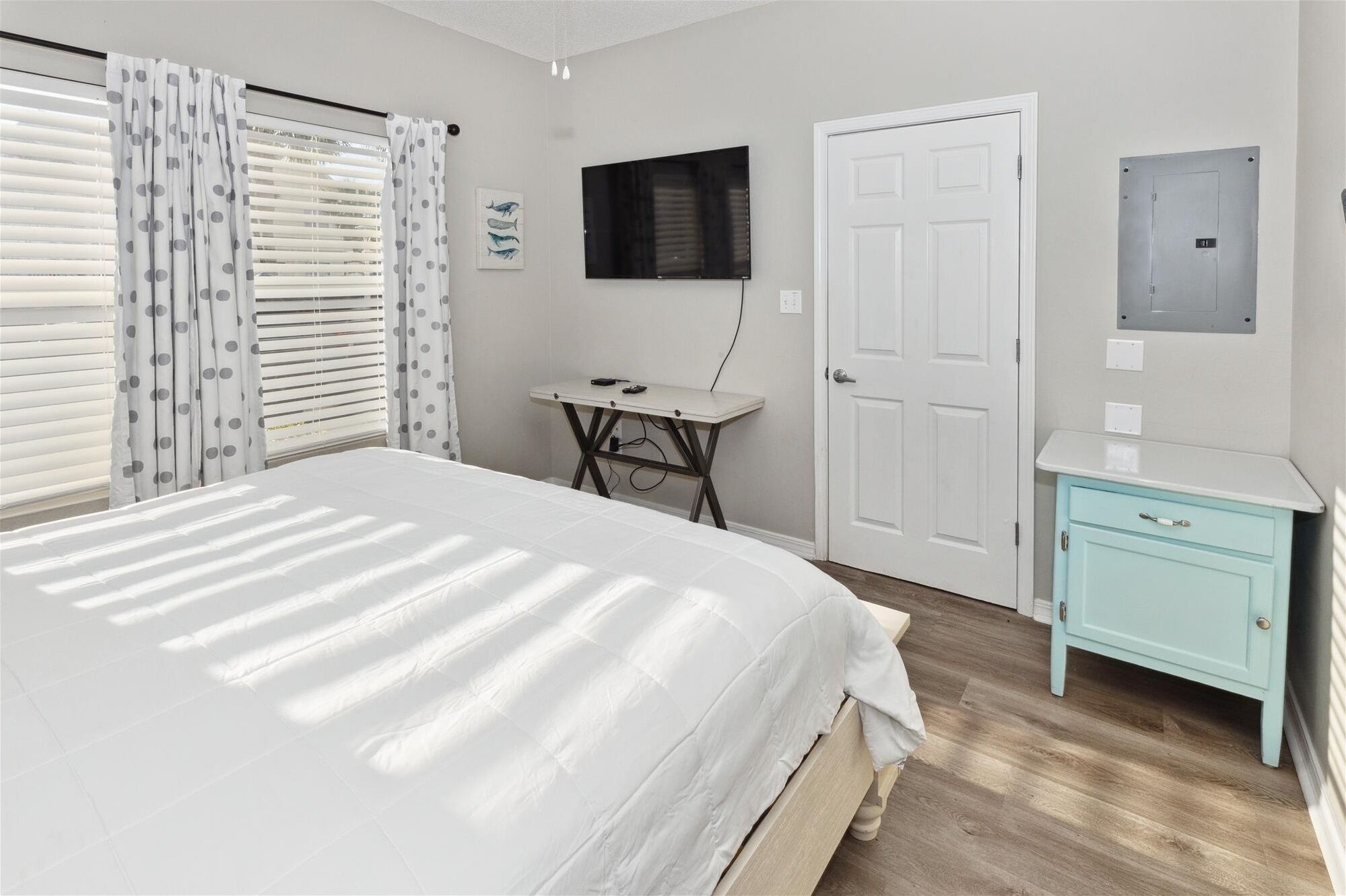 A bedroom with a bed, a desk, a television, and a wardrobe.