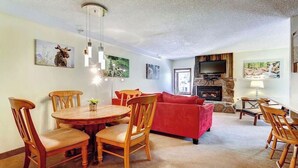 Ein gemütliches Wohnzimmer mit Kamin, eine Essecke mit Holzmöbeln und ein rotes Sofa.