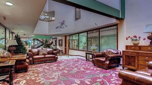 Eine großzügige Lobby mit Ledersofas, einem gemusterten Teppich und einer Treppe zu einer oberen Ebene.