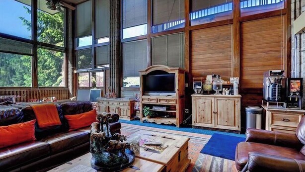 Ein geräumiges Wohnzimmer mit großem Fenster, einer Holz-Unterhaltungseinrichtung und einer Kaffeemaschine.