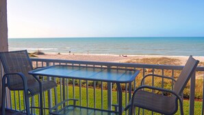 Varanda com mesa e cadeiras com vista para a praia.
