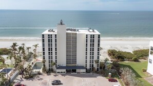 Um hotel alto com vista para a praia, vários andares e estacionamento.