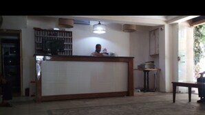 A reception area with a counter, a television, and a ceiling light fixture. - De La Poste (Port Said)