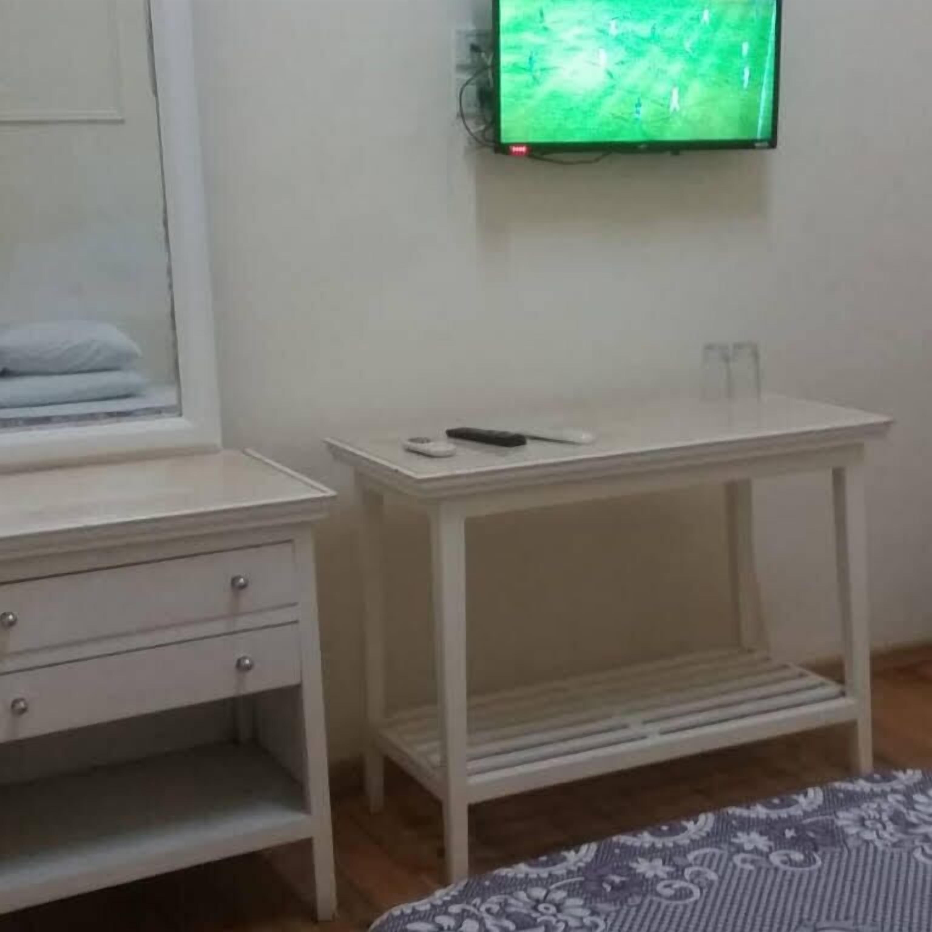 Une chambre d’hôtel avec un lit, une table de chevet avec une télécommande, une petite table et une fenêtre donnant sur un paysage verdoyant.