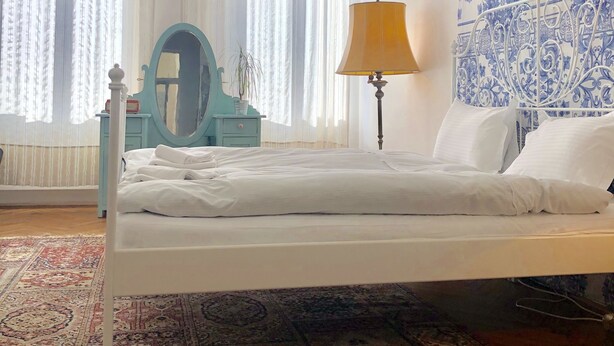 A bedroom with a bed, a nightstand, a lamp, a mirror, and a patterned wall. - Camino Home (Cluj-Napoca)