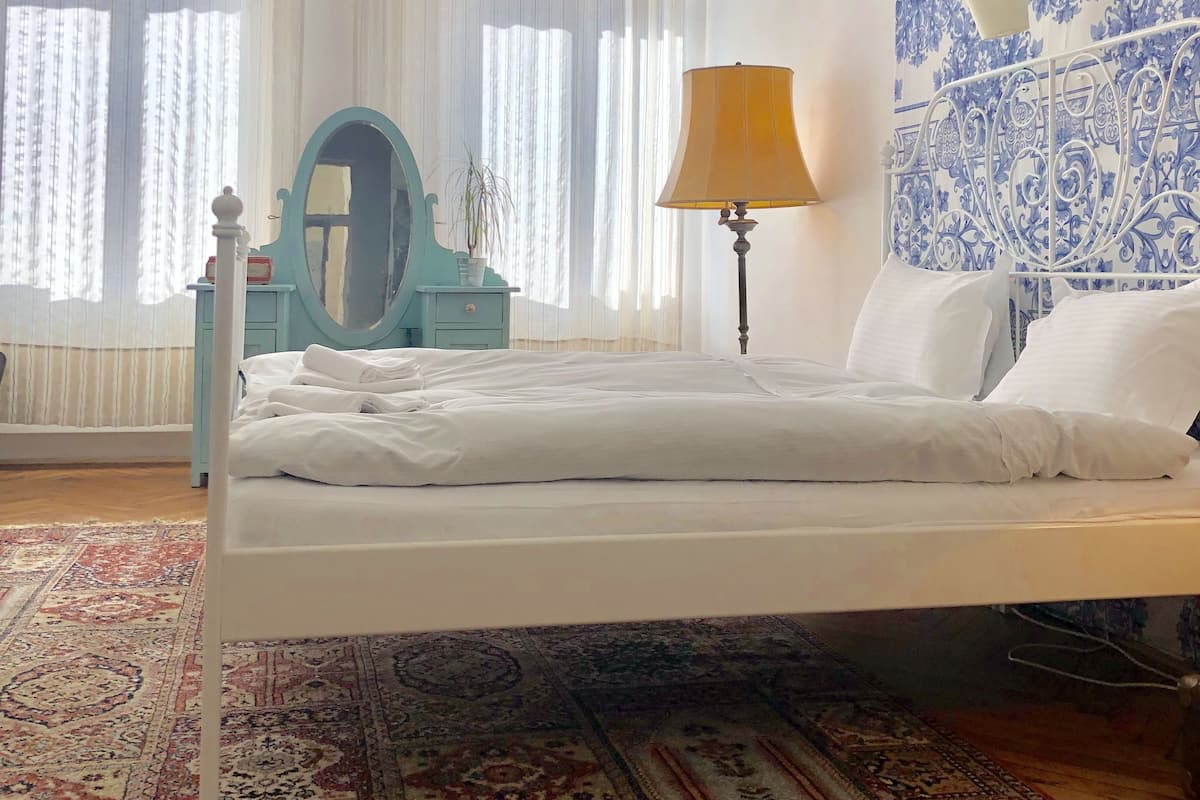 Un dormitorio con cama, mesita de noche, lámpara, espejo y pared con diseño.