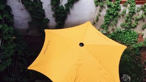 A yellow umbrella with a logo on a tiled patio area. - Camino Home (Cluj-Napoca)