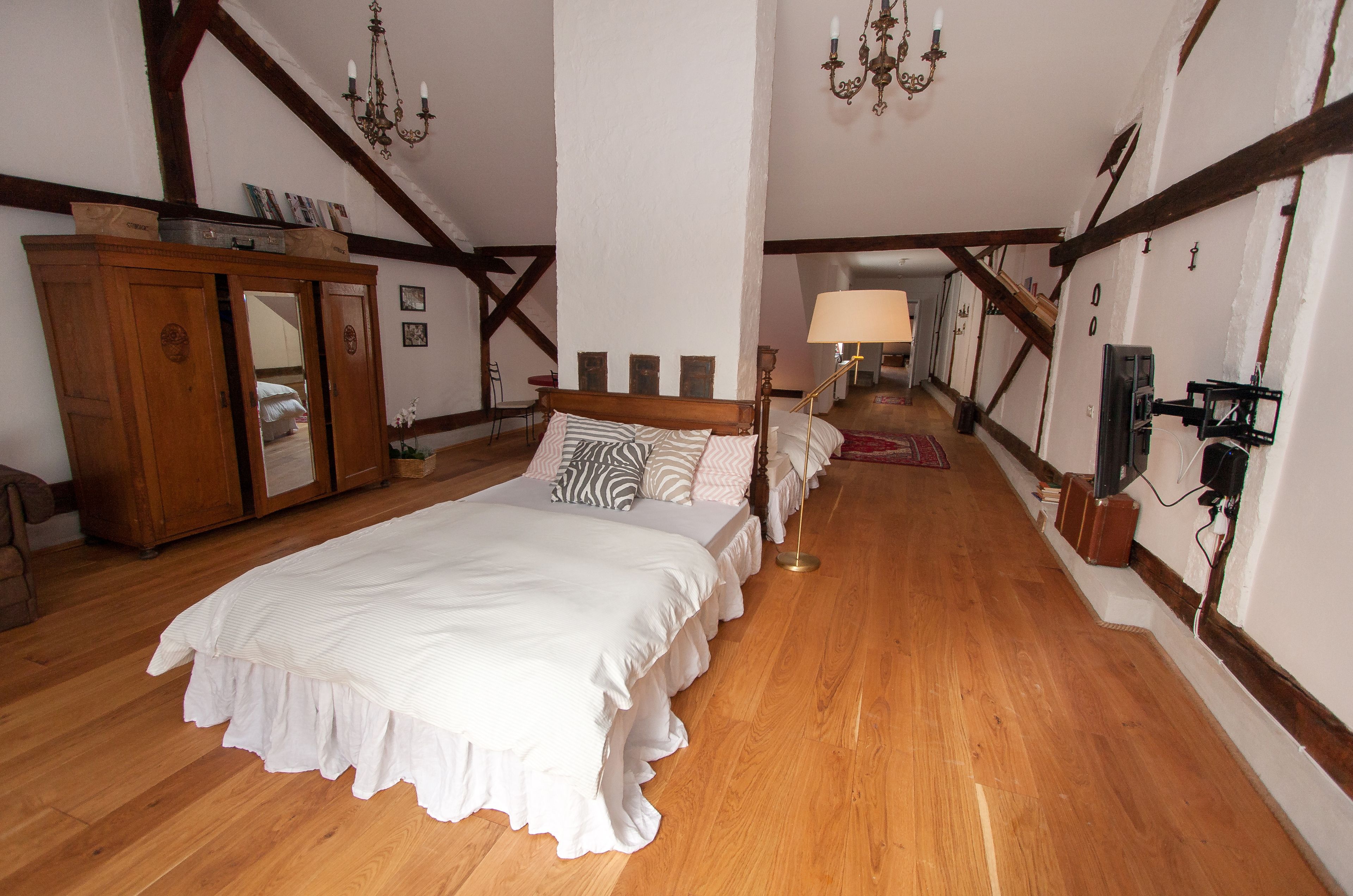 Een slaapkamer met een groot bed, een houten kledingkast en een kroonluchter.