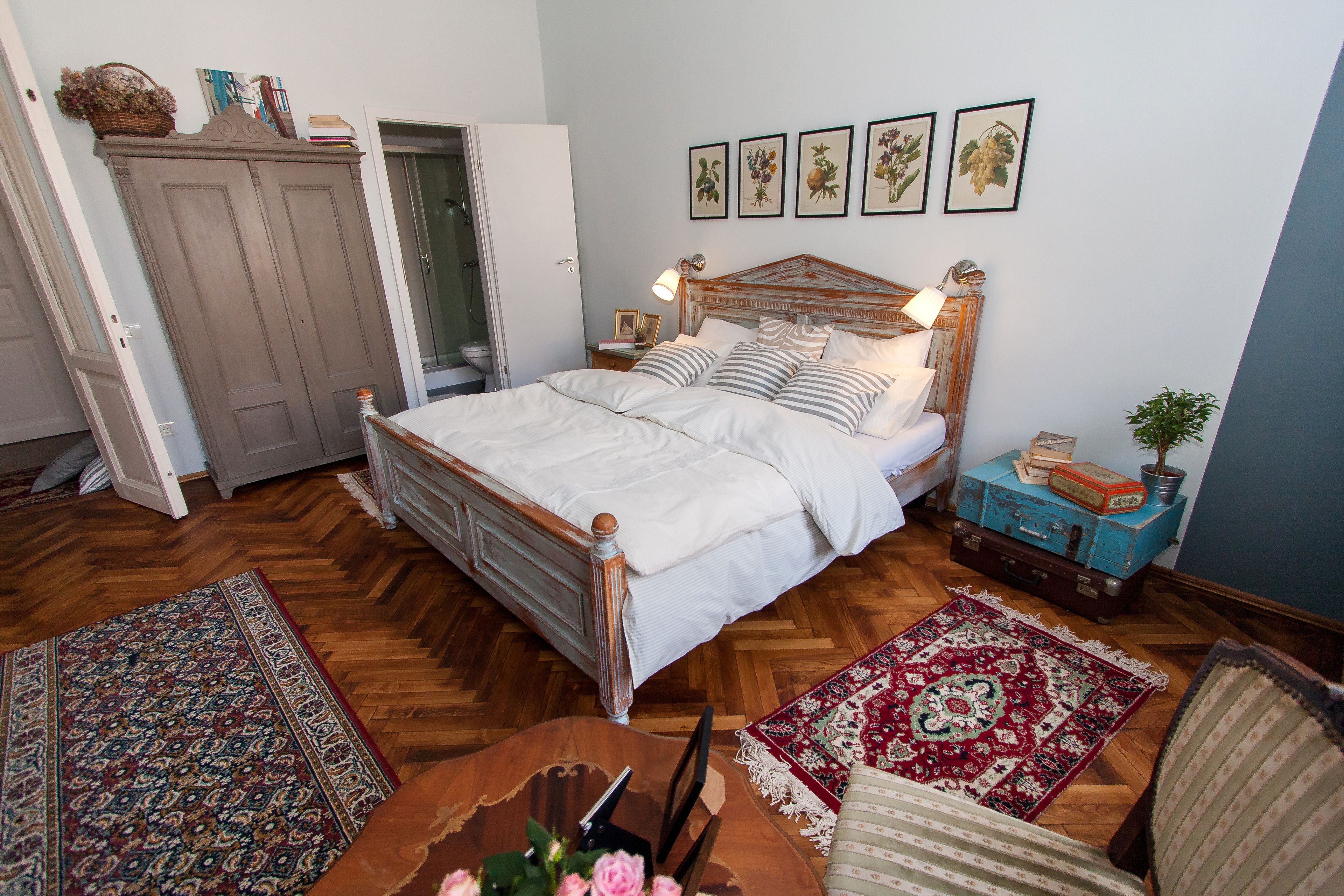 A bedroom with a wooden bed, a nightstand, a lamp, a dresser, and a red and white patterned rug.