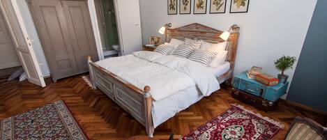 A bedroom with a wooden bed, a nightstand, a lamp, a dresser, and a red and white patterned rug.