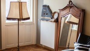 A room with a wooden floor, a standing lamp, a mirror, and a small table with a clock. - Camino Home (Cluj-Napoca)
