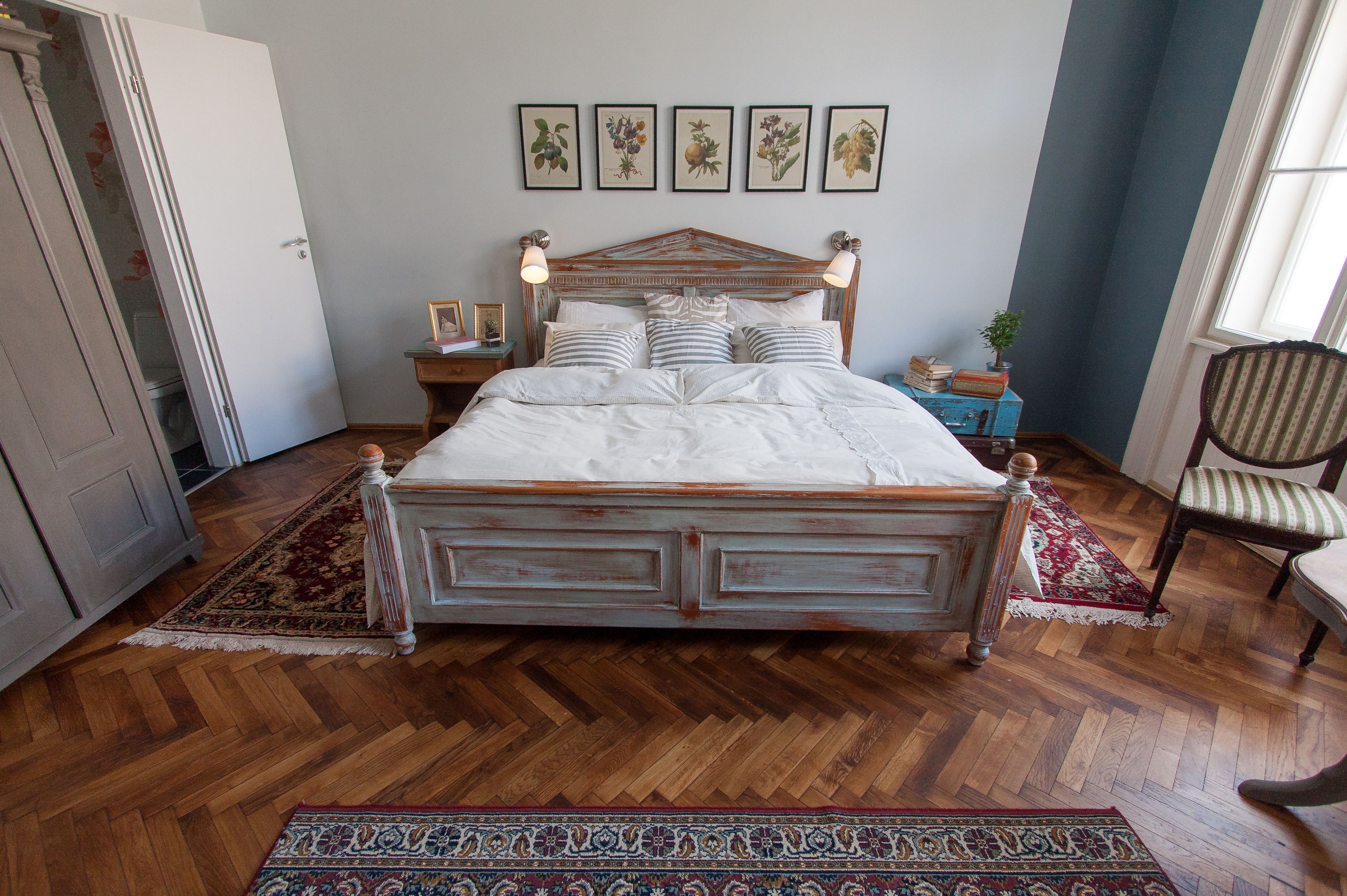 A bedroom with a wooden bed, a nightstand, a chair, and a window.