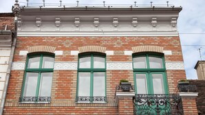 A building with three arched windows with green frames and white shutters, a decorative white cornice, and a brick facade. - Camino Home (Cluj-Napoca)