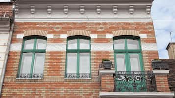 Fachada de edificio con tres ventanas arqueadas, pared de ladrillo y molduras decorativas.